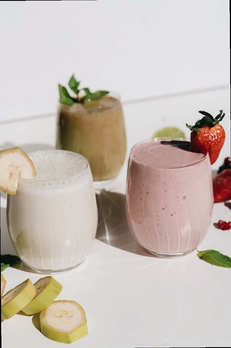 Tres refrescantes batidos de frutas con luz natural y guarniciones de frutas.