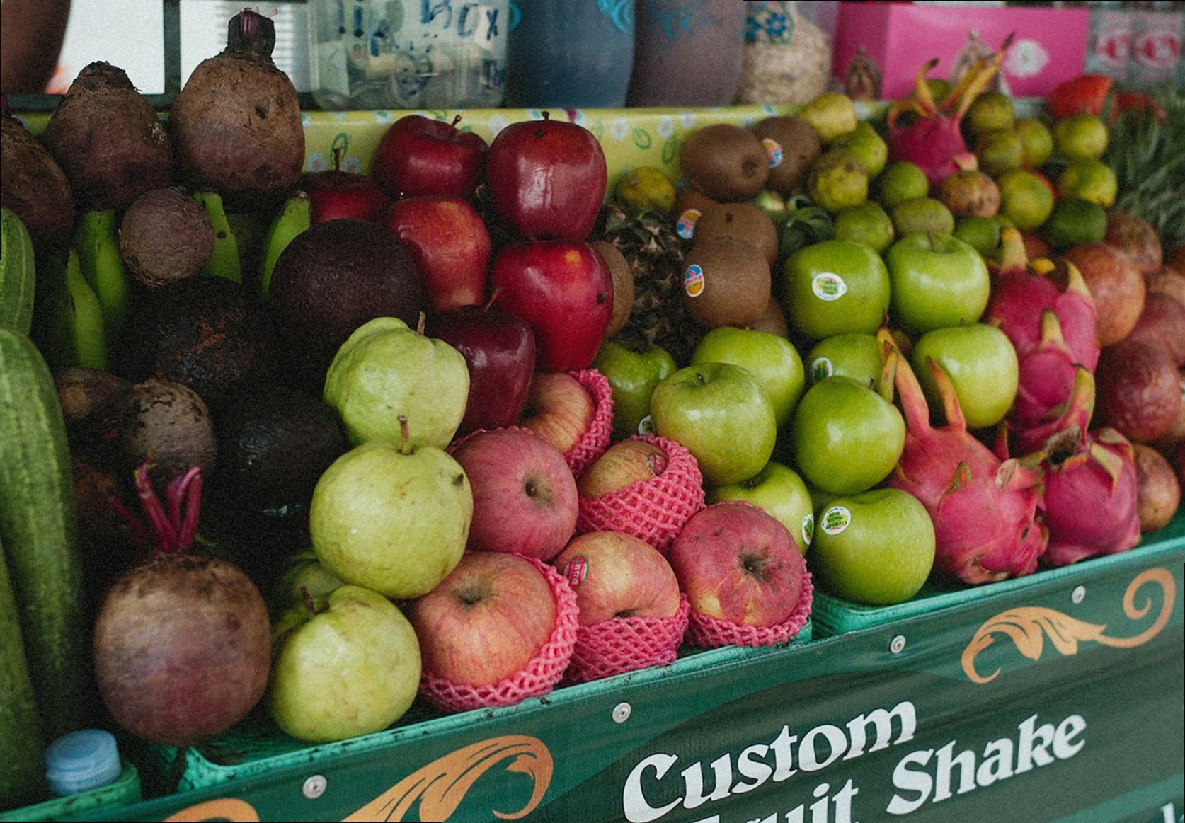 Una vibrante variedad de frutas frescas en un mercado al aire libre que ofrece batidos de frutas personalizados.
